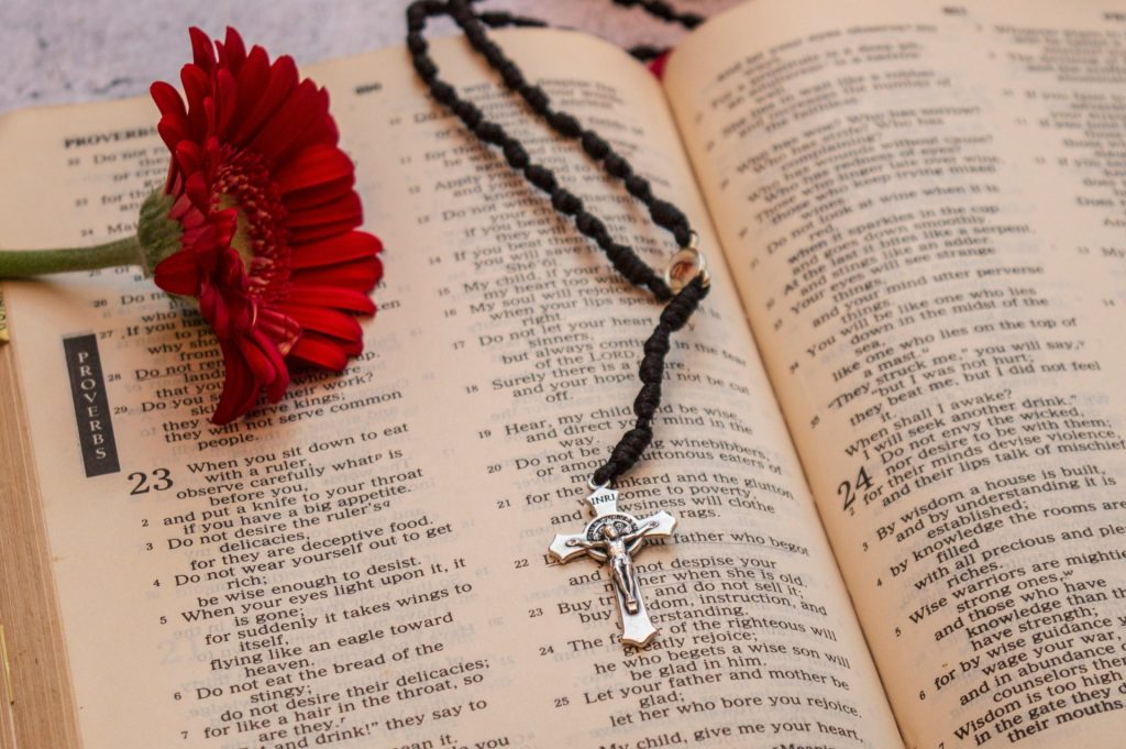 silver crucifix pendant necklace on book page